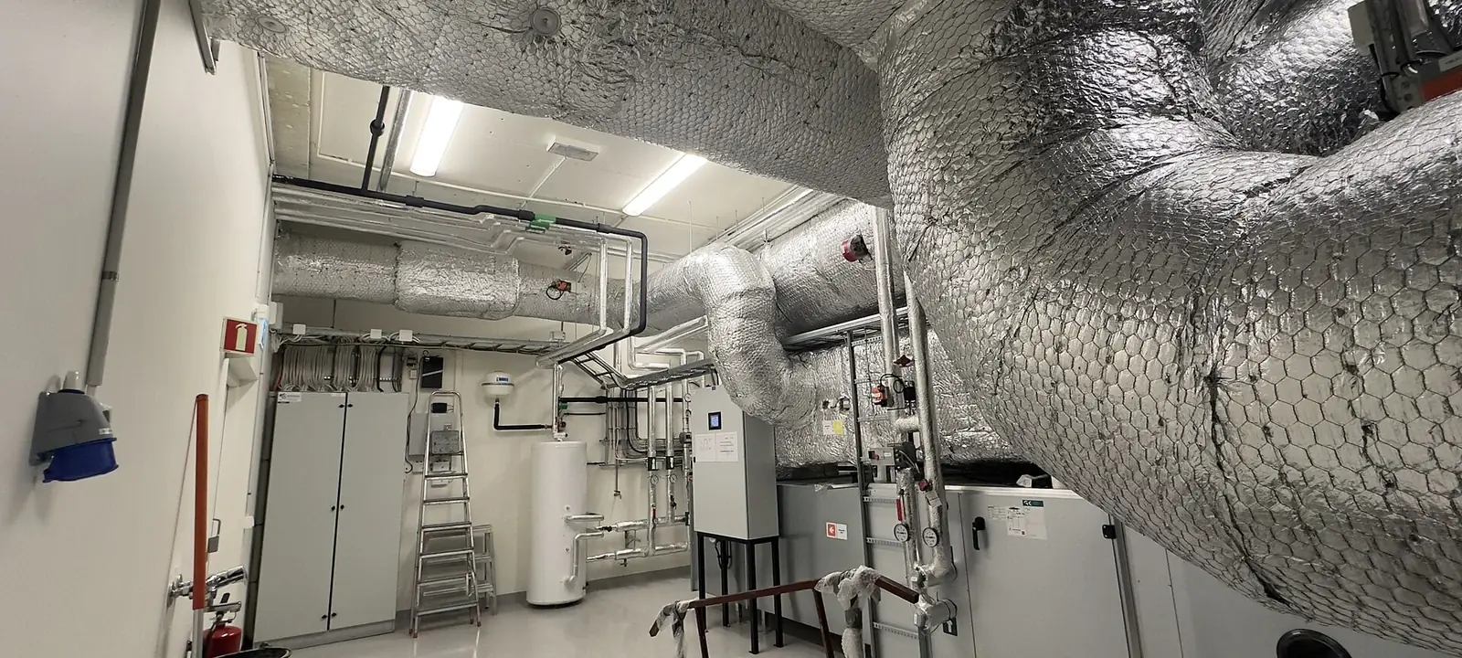 Mechanical room with insulated heating pipes, boilers and a water heater