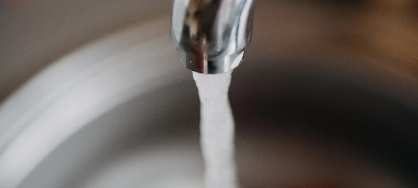 Water flowing from a chrome faucet into a sink